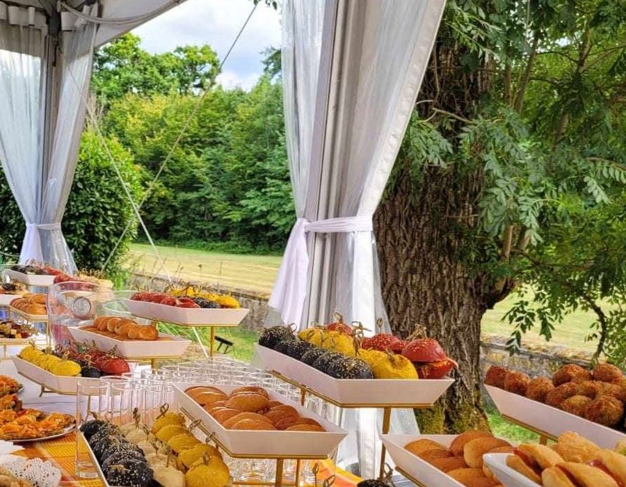 Le buffet dressé sous une tente blanche, dans un jardin.
